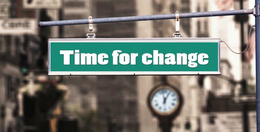 the words "time for change" written on a street sign in front of a clock