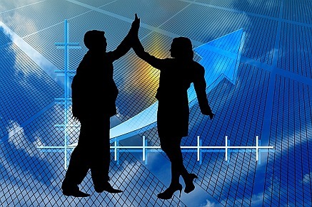 silhouette of man and woman doing a high 5 in front of success graph