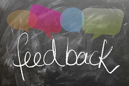 the word "feedback" written on a chalkboard with colored callout boxes above it